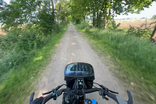 Blick vom Fahrrad auf einen Fahrradweg im Grünen